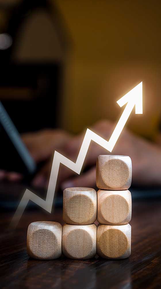 Fluctuation zigzag arrow rising on wooden cube blocks as graph steps while businessperson working with laptop computer. Business market growth, goal and success, progress and management concepts.